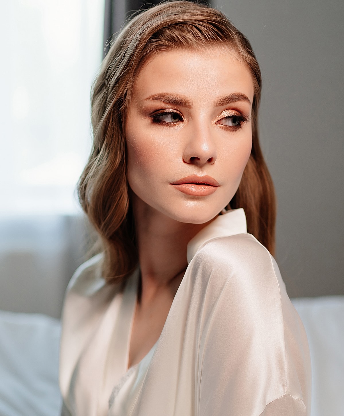 Woman with soft makeup in satin robe.