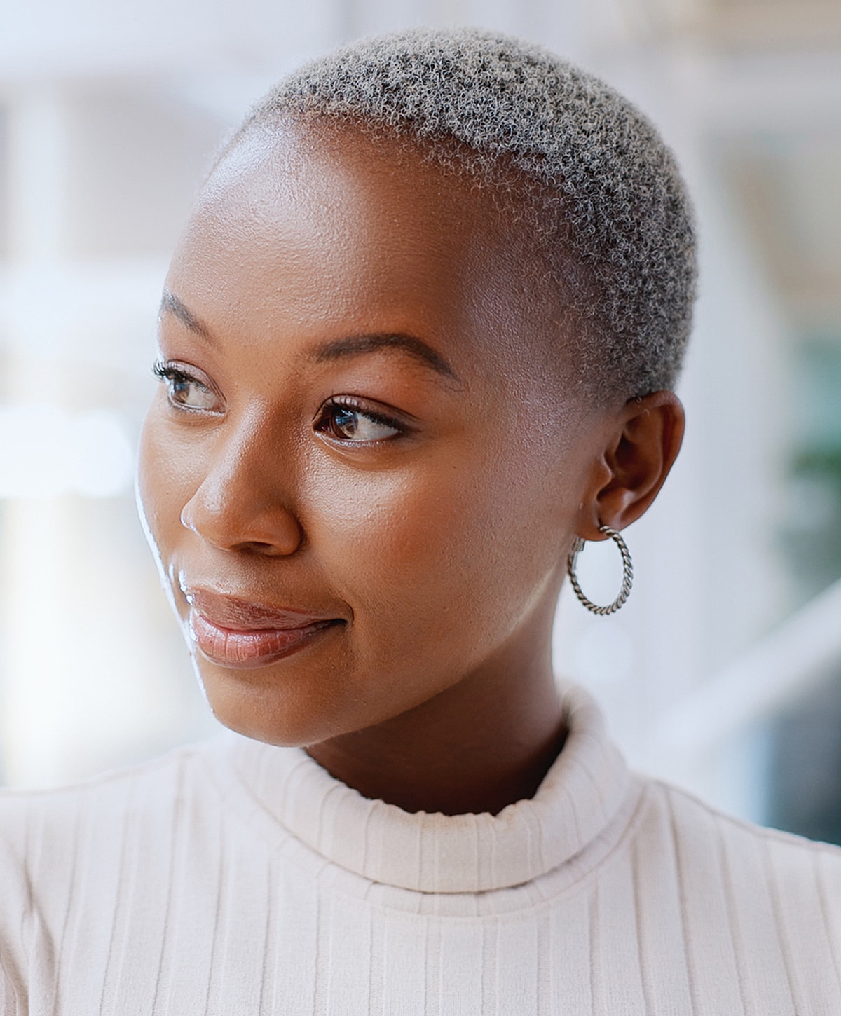 Woman with short grey hair wearing hoop earrings.