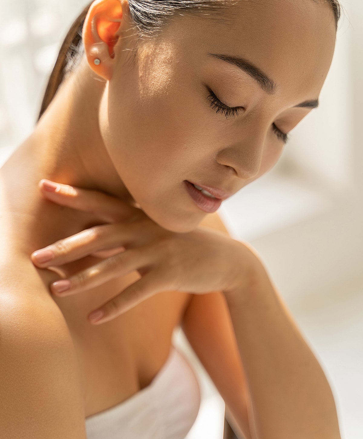Woman in soft light with gentle expression.